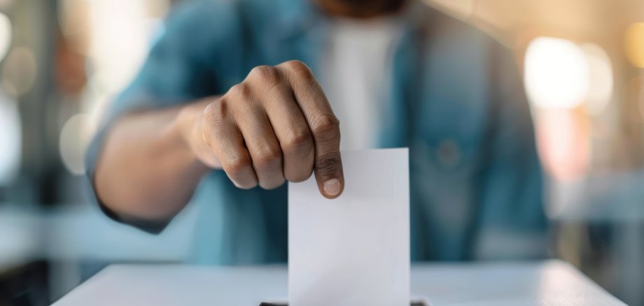 Une personne dépose un bulletin dans une urne.